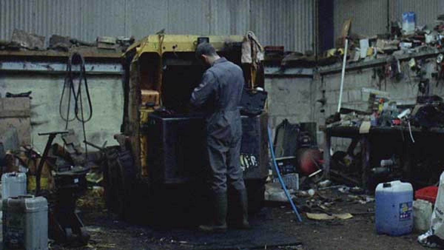 A still from the film 'Landline' showing a young farmer doing maintenance on his Land Rover A still from the film 'Landline' showing a young farmer doing maintenance on his Land Rover